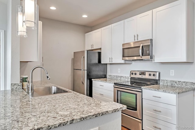 14251 E 1st Dr Unit 308, Aurora, CO 80011 - kitchen featuring appliances with stainless steel finishes, a sink, white cabinetry, recessed lighting, and light stone countertops