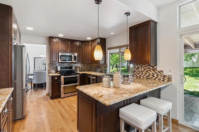 5625 W 109th Cir, Westminster, CO 80020 - kitchen featuring appliances with stainless steel finishes, light wood-style floors, a peninsula, decorative backsplash, and recessed lighting