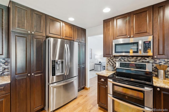 5625 W 109th Cir, Westminster, CO 80020 - kitchen featuring stainless steel appliances, light wood-style flooring, tasteful backsplash, light stone counters, and recessed lighting