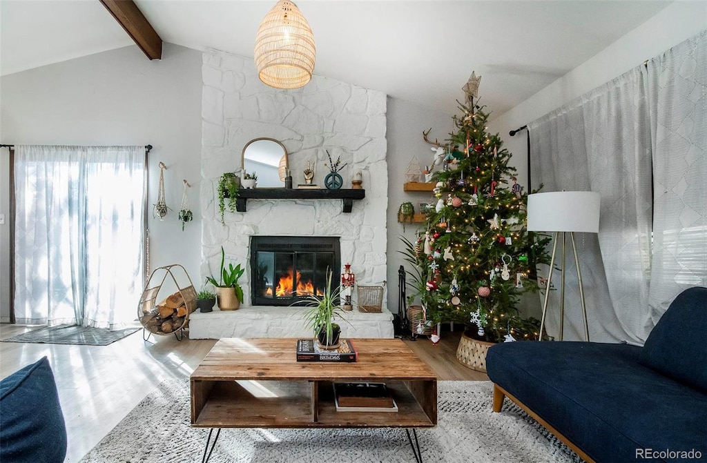 living room with vaulted ceiling with beams, light wood-type flooring, and a fireplace