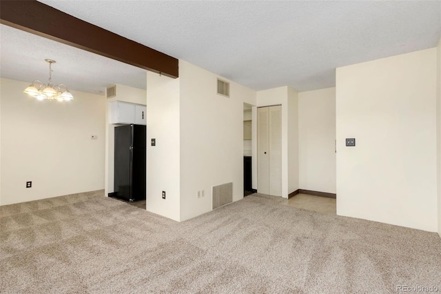 carpeted empty room featuring beamed ceiling, a textured ceiling, and a notable chandelier