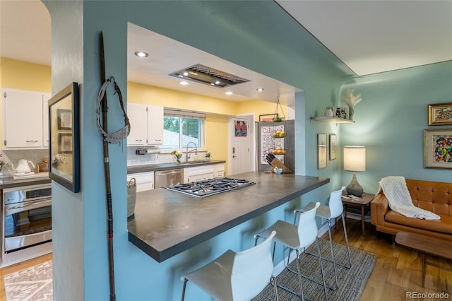4891 Depew St, Denver, CO 80212 - kitchen featuring stainless steel appliances, dark countertops, a peninsula, white cabinets, and tasteful backsplash