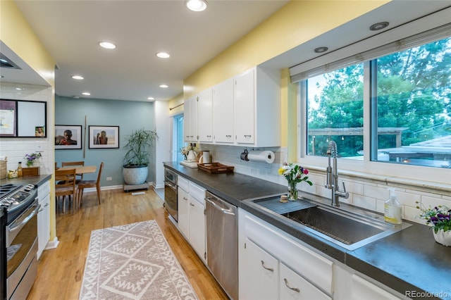 4891 Depew St, Denver, CO 80212 - kitchen featuring appliances with stainless steel finishes, dark countertops, backsplash, white cabinets, and light wood-type flooring