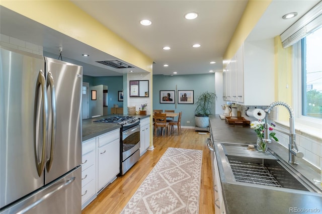 4891 Depew St, Denver, CO 80212 - kitchen featuring stainless steel appliances, dark countertops, white cabinets, light wood finished floors, and recessed lighting