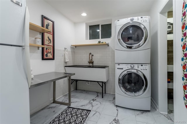 4891 Depew St, Denver, CO 80212 - laundry area featuring stacked washing machine and dryer, light marble finish floors, recessed lighting, and tile walls