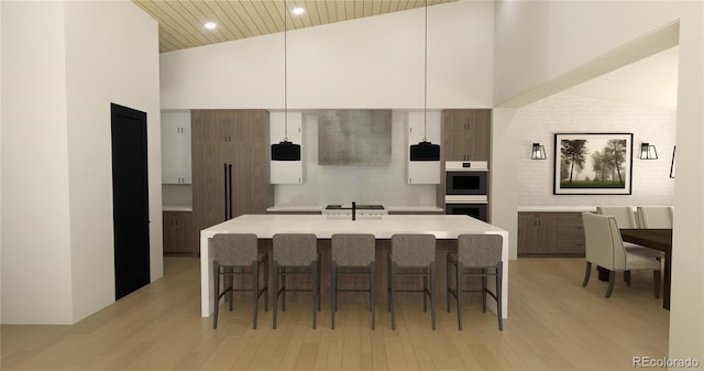 7142 Lynx Lair Rd, Evergreen, CO 80439 - kitchen with high vaulted ceiling, white double oven, light wood finished floors, a breakfast bar, and light countertops