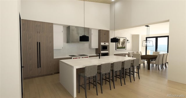 7142 Lynx Lair Rd, Evergreen, CO 80439 - kitchen featuring a high ceiling, light wood-style floors, a kitchen bar, light countertops, and a center island with sink