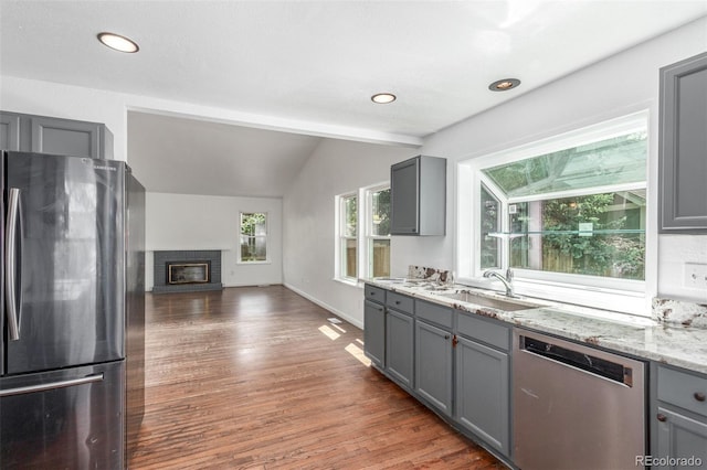 2026 S Pitkin St, Aurora, CO 80013 - kitchen with appliances with stainless steel finishes, gray cabinetry, a sink, wood finished floors, and light stone countertops
