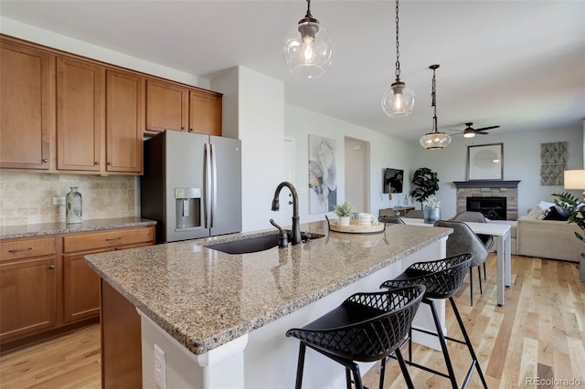 5528 Echo Hollow St, Castle Rock, CO 80104 - kitchen with stainless steel refrigerator with ice dispenser, ceiling fan, light wood-style floors, decorative light fixtures, and a fireplace