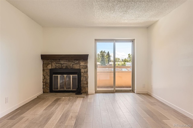 unfurnished living room featuring wood finished floors, a textured ceiling, a fireplace, and baseboards