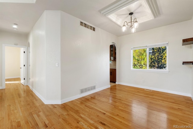 unfurnished room featuring a chandelier and light hardwood / wood-style flooring