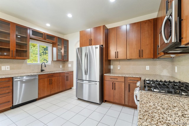 kitchen featuring decorative backsplash, sink, light stone countertops, and appliances with stainless steel finishes