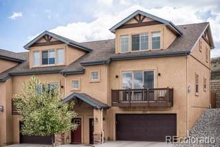 5703 Canyon Reserve Hts, Colorado Springs, CO 80919 - view of front facade featuring a garage, a balcony, stucco siding, a shingled roof, and concrete driveway