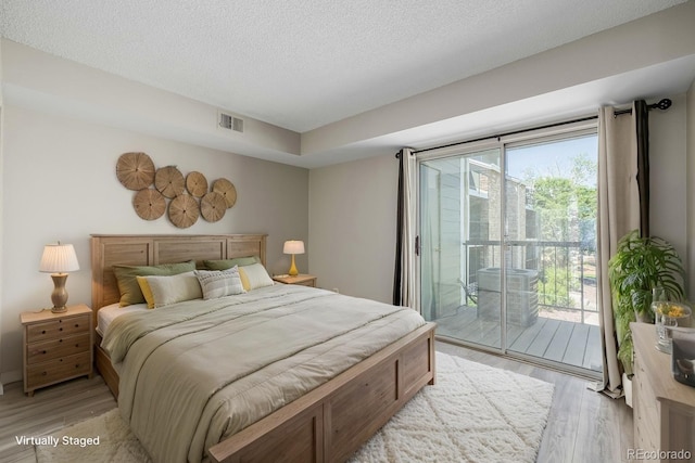 8843 Colorado Blvd Unit 208, Thornton, CO 80229 - bedroom featuring access to outside, light wood-type flooring, multiple windows, and a textured ceiling