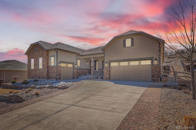 view of front of property with stone siding, concrete driveway, roof with shingles, and fence