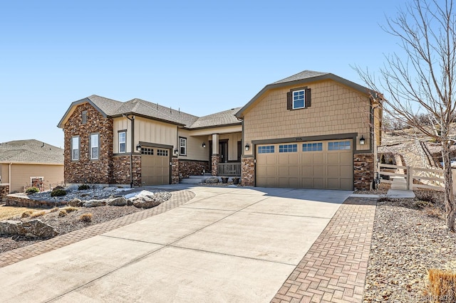 view of front of house with fence, driveway, a shingled roof, stone siding, and board and batten siding