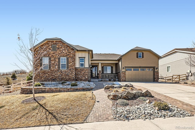 craftsman house featuring stone siding, board and batten siding, concrete driveway, and fence