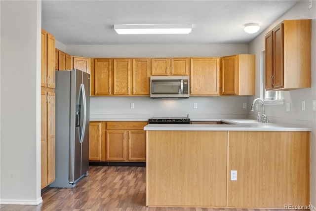 9638 Marion Way, Thornton, CO 80229 - kitchen featuring appliances with stainless steel finishes, wood finished floors, a peninsula, light countertops, and a sink