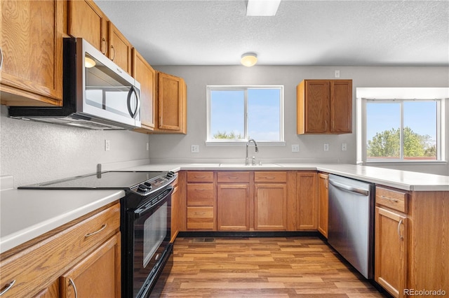 9638 Marion Way, Thornton, CO 80229 - kitchen featuring stainless steel appliances, a sink, plenty of natural light, light wood-style flooring, and a textured ceiling