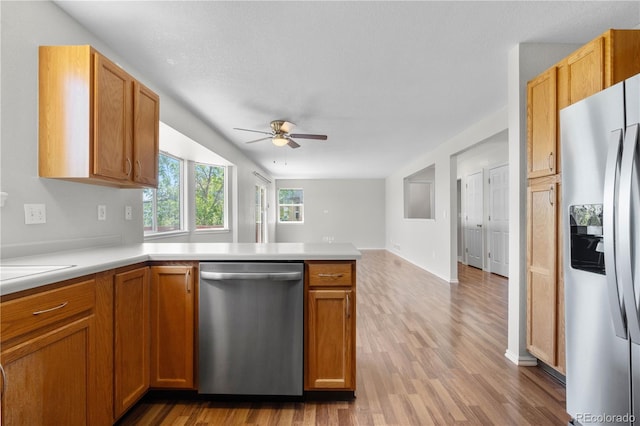 9638 Marion Way, Thornton, CO 80229 - kitchen featuring stainless steel appliances, a ceiling fan, a peninsula, light countertops, and light wood-style flooring