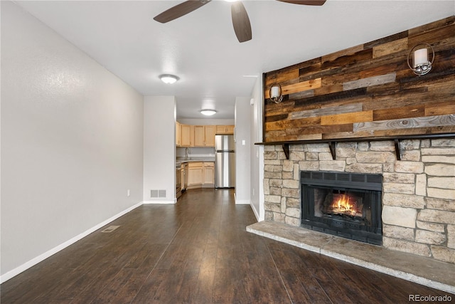 unfurnished living room featuring visible vents, baseboards, a fireplace, ceiling fan, and dark wood finished floors