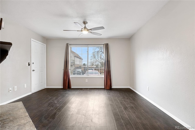 unfurnished room with baseboards, a textured ceiling, dark wood-style floors, and a ceiling fan