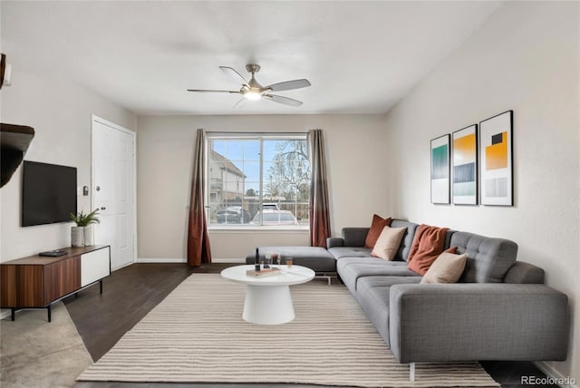 living room with a ceiling fan, baseboards, and wood finished floors