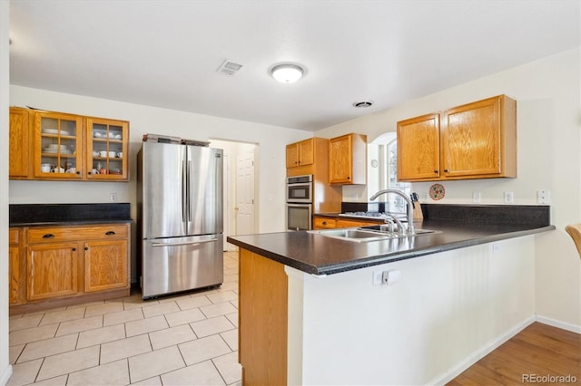 kitchen with kitchen peninsula, sink, stainless steel appliances, and light wood-type flooring