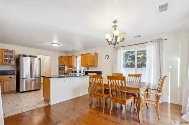 dining space with light hardwood / wood-style floors, sink, and an inviting chandelier