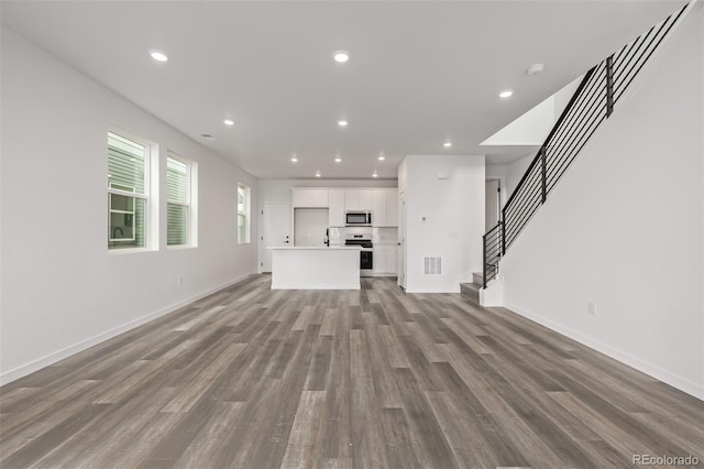 20520 E 58th Ave, Aurora, CO 80019 - unfurnished living room featuring wood finished floors, stairway, recessed lighting, and baseboards