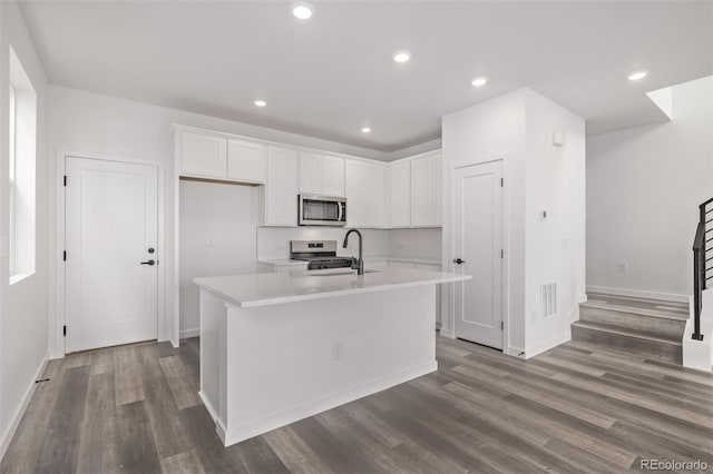 20520 E 58th Ave, Aurora, CO 80019 - kitchen featuring appliances with stainless steel finishes, white cabinets, wood finished floors, light countertops, and a center island with sink