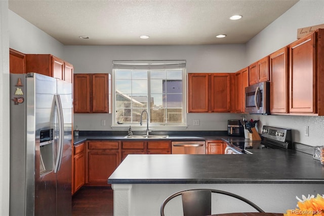 kitchen with sink, appliances with stainless steel finishes, dark hardwood / wood-style floors, a textured ceiling, and kitchen peninsula