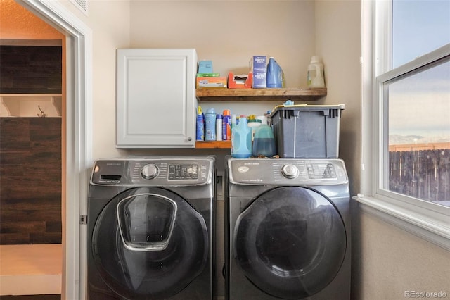 clothes washing area featuring cabinets and washer and dryer