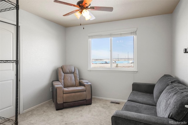 living area featuring ceiling fan and light colored carpet