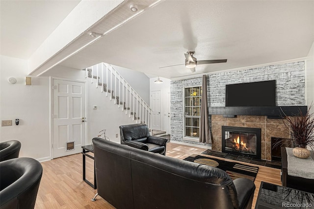 living room featuring ceiling fan, light wood-type flooring, and a fireplace