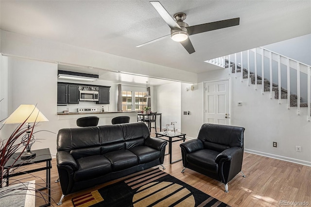 living room with ceiling fan, light hardwood / wood-style flooring, and a textured ceiling