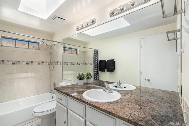 full bathroom with a skylight, tile patterned floors, vanity, shower / bath combo with shower curtain, and toilet