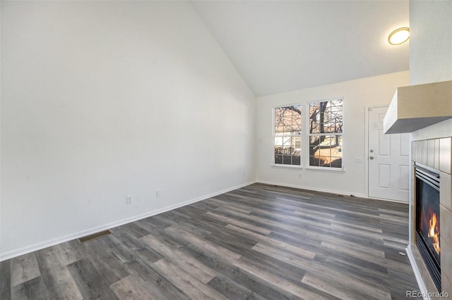 unfurnished living room with high vaulted ceiling and dark wood-type flooring