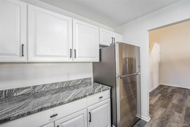 kitchen with white cabinetry, stainless steel refrigerator, dark wood-type flooring, and dark stone countertops