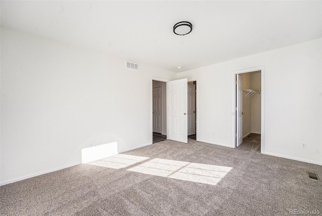 unfurnished bedroom featuring a spacious closet, a closet, and carpet floors