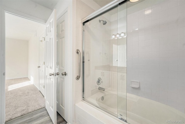 bathroom with hardwood / wood-style flooring and bath / shower combo with glass door