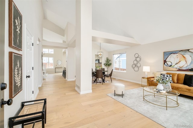 living room with high vaulted ceiling, light wood-type flooring, and a notable chandelier