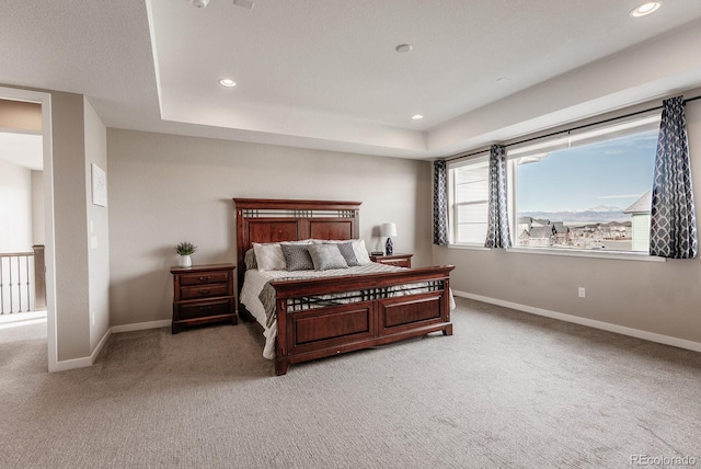 bedroom with a tray ceiling, recessed lighting, baseboards, and light carpet