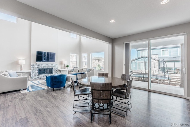 dining area featuring recessed lighting, wood finished floors, and a tiled fireplace