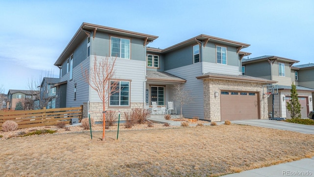 view of front of property with a garage, stone siding, driveway, and fence