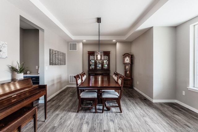 dining room with visible vents, baseboards, a tray ceiling, recessed lighting, and wood finished floors