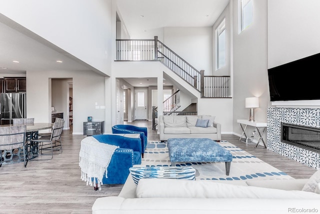 living room featuring baseboards, light wood-style floors, a healthy amount of sunlight, and a tiled fireplace