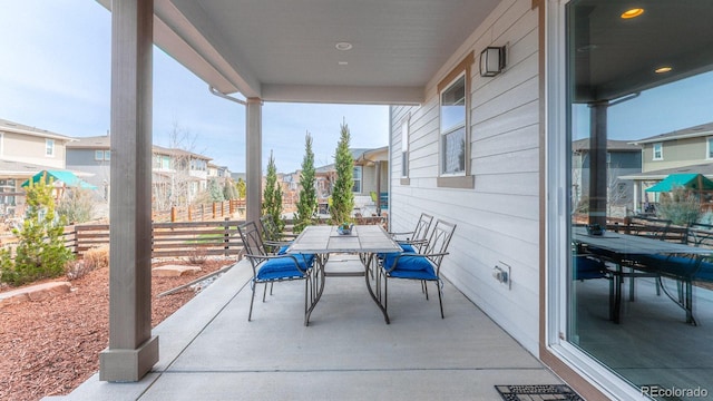 view of patio featuring a residential view, outdoor dining area, visible vents, and fence