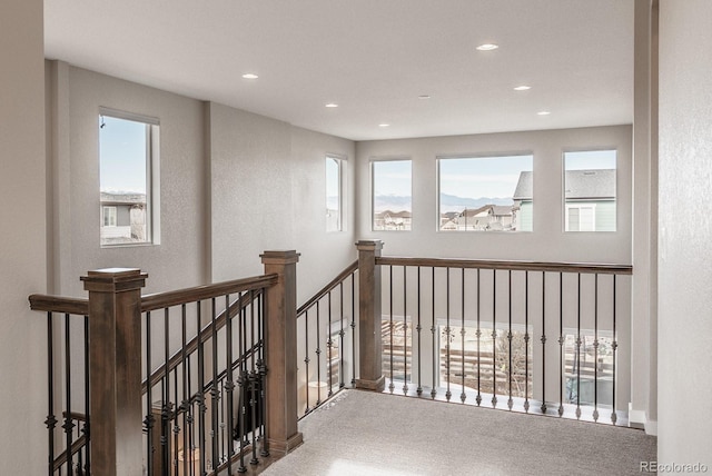 hall featuring an upstairs landing, plenty of natural light, and recessed lighting