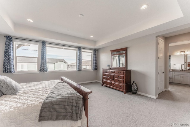 bedroom with light colored carpet, a raised ceiling, and baseboards